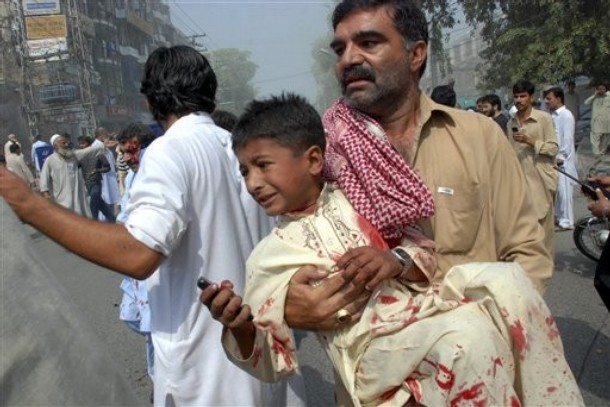 Pakistani volunteer takes away an injured boy from the site of a bomb explosion in a commercial district in Peshawar, Pakistan on Saturday, Sept. 26, 2009